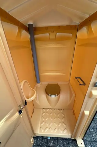 Kleine draagbare toiletcabine met open deur en basisinterieur