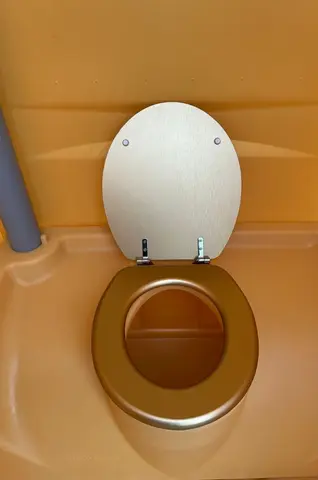 Een eenvoudige toiletbril in een kleine cabine met zachte gele wanden