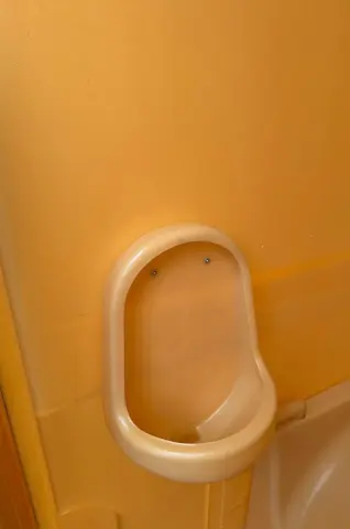 Een compact urinoir gemonteerd op een gladde gele achtergrond