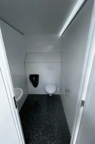 Moderne compacte badkamer met toilet wastafelmeubel en rechthoekige spiegel; neutrale tinten en strak ontwerp
