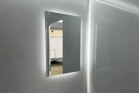 Een lichte badkamer met een rechthoekige spiegel aan de wand