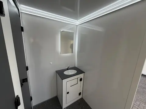 Binnenkant van een nette badkamer met toilet wastafel en ronde spiegel passend bij de vacuum toiletwagen GL A van Europe Wagon
