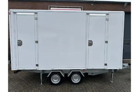 Zijkant van een ruime witte aanhanger met stevige sloten en twee paar wielen