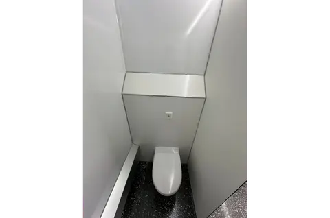 Een klein toilet in een smalle ruimte met lichte wanden