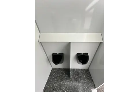 Twee urinoirs tegen een gladde wand in een compacte sanitaire ruimte