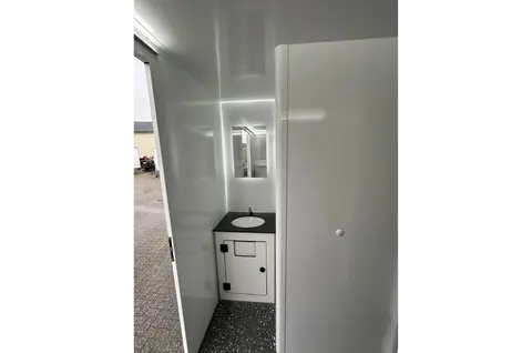Witte sanitaire ruimte met een wastafelmeubel en deur naar buiten