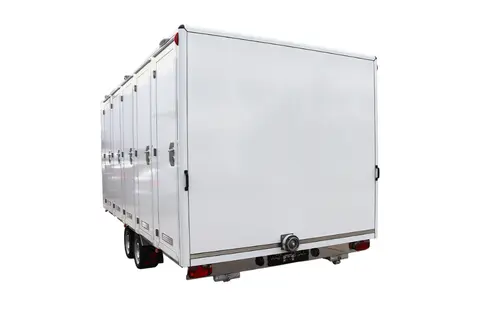 Een witte gesloten aanhangwagen gezien vanaf de achterkant met meerdere deuren aan de zijkant