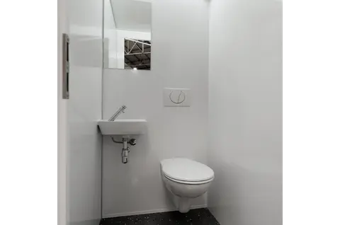 Kleine witte toiletruimte met een hangtoilet een compact fonteintje en een spiegel aan de muur