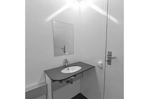 GM C Handicap met douche Kleine badkamer met een wastafel spiegel en deur in een witte ruimte