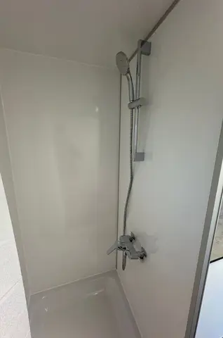 Douchecabine met een moderne zilveren douchekop en gladde witte wanden
