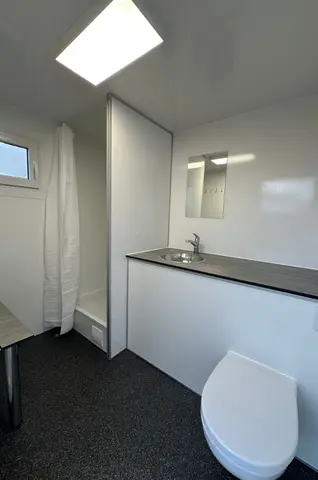 Een kleine frisse badkamer met een douche wastafel en toilet
