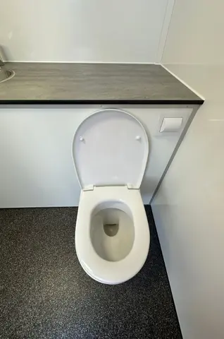 Witte toiletpot met open deksel in een kleine nette badkamer