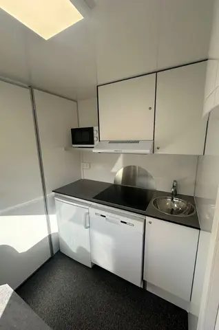 Een kleine lichte keuken met een spoelbak koelkast en magnetron
