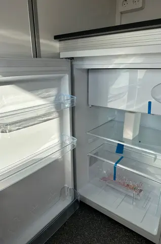 Een open koelkast met lege planken en bakken